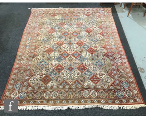 A 1960s Persian Koum or Kum carpet of red, salmon pink, blue and oatmeal colours, the central diamond trellis patterned field