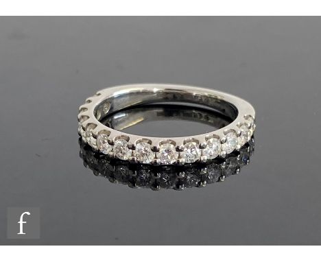 A platinum hallmarked diamond half eternity ring, comprising fourteen claw set brilliant cut stones, total weight approximate