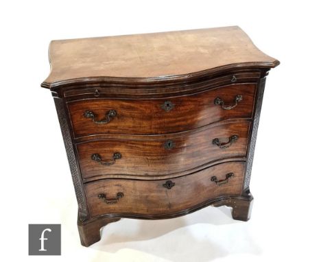 A George III style mahogany serpentine chest of three long drawers below a leather inset brushing slide flanked by blind fret