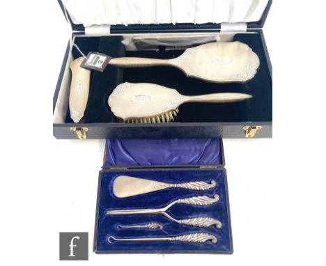 A cased hallmarked silver backed four piece brush set with engine turned decoration, with a cased silver handled button hook,