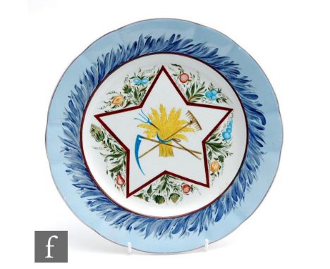 An early 20th Century Russian plate, later hand painted with a scythe, rake and fork through a bundle of wheat, all within a 