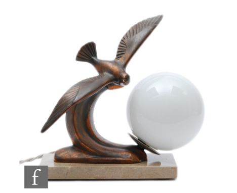 A 20th Century French patinated spelter table lamp, decorated with a bird in flight over a crashing wave, with an opaque whit