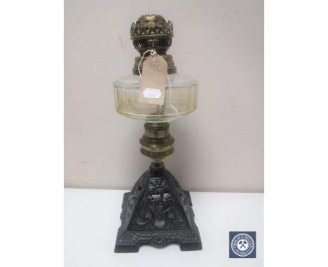 A Victorian oil lamp with glass reservoir on cast metal base