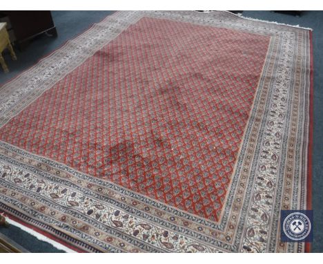 A machine made fringed carpet on red ground 