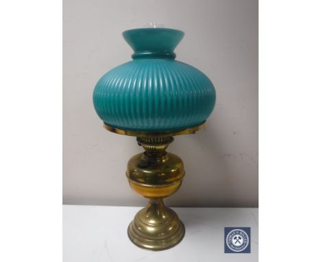 An early 20th century brass oil lamp with chimney and green glass shade 