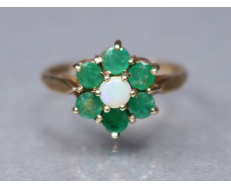A 9ct. gold dress ring set opal within a border of small emeralds; size: Q/R; 2.9gm.