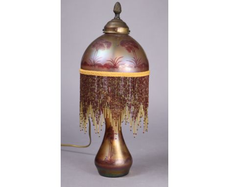 An Art Nouveau Loetz-style iridescent glass & copper table lamp, hung with beaded tassels from the domed shade & painted with