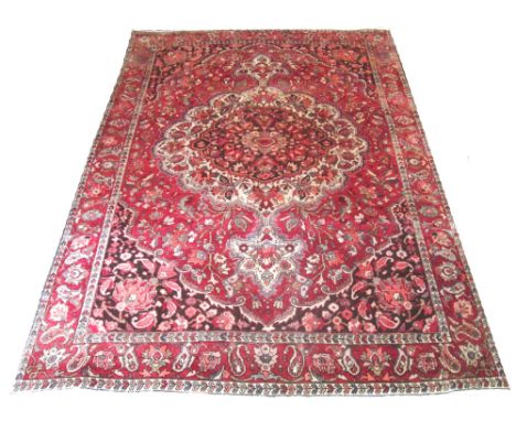 BAKTIAR CARPET, 305cm x 210cm, large organic medallion on a ruby field of scrolling palmettes and vines within corresponding 