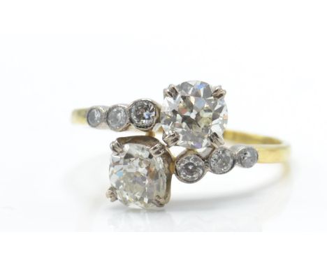 An 18ct gold and diamond cross over ring. The ring being set with 2 old cut diamonds flanked by graduating bezel set diamonds