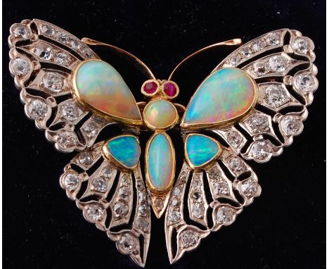 An Edwardian opal, ruby and diamond butterfly pendant brooch. The butterfly body formed with a round and an oval opal cabocho