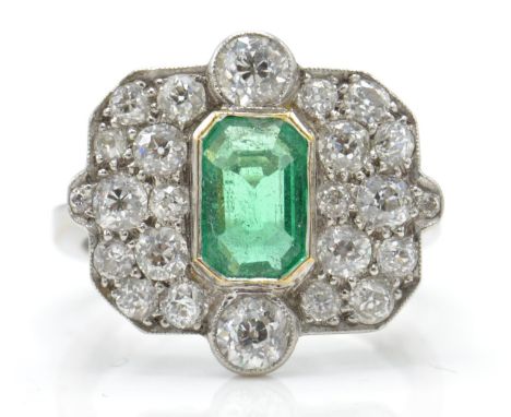 An 18ct white gold emerald and diamond ring. The ring set with a central octagon cut emerald flanked by 2 old cut diamonds wi