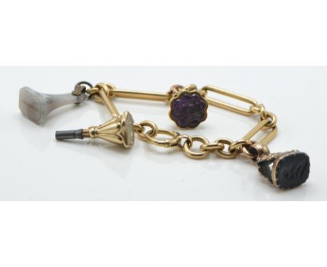An 18ct gold charm bracelet. The 18ct stretch link bracelet ( tests ) set with a 14ct gold intaglio clock key charm, 9ct Inta