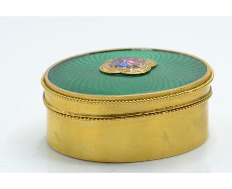 A French 18ct gold and enamel dressing table vanity pot. The pot of oval form having a central enamel floral cartouche set up