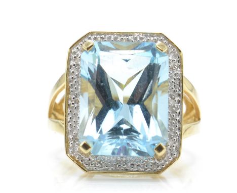 A 14ct aquamarine and diamond ring. The ring set with a large emerald cut aquamarine surrounded by diamonds in an illusion se