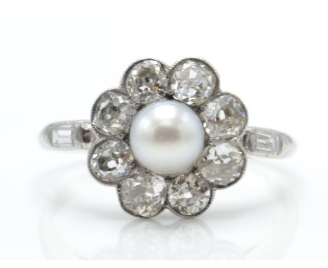 A platinum diamond and pearl cluster ring. The ring set with a central natural pearl surrounded by a halo of old cut diamonds