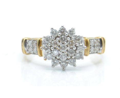 A hallmarked 9ct gold and diamond cluster ring. The ring set with a central cluster of diamonds with diamond set shoulders. H