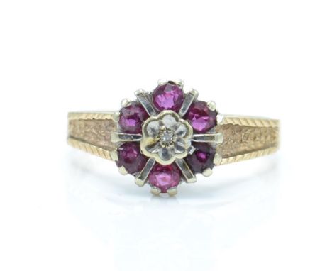 A 1970's hallmarked 9ct gold ruby and diamond cluster ring. The ring having a central illusion set diamond surrounded by a ha