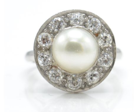 A platinum pearl and diamond cluster ring. The ring set with a large pearl surrounded by a halo of diamonds. Estimated total 