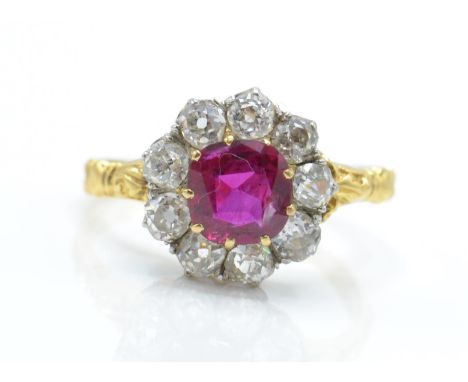 A 14ct gold ruby and diamond cluster ring. The ring set with a cushion cut burmese ruby surrounded by old cut diamonds estima