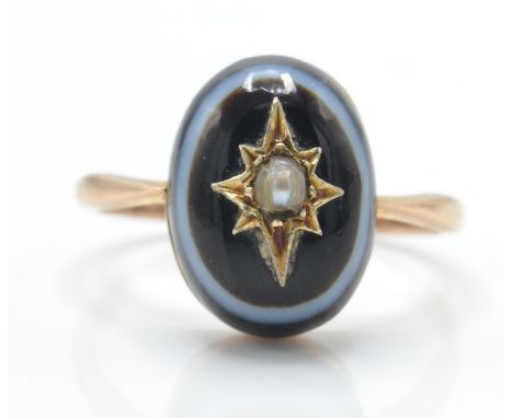 An antique 9ct gold banded agate and pearl ring. The ring being set with a central half pearl within a star mounted banded ag