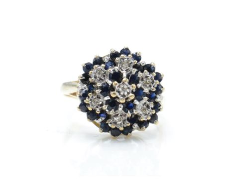 A hallmarked 9ct gold sapphire and diamond cluster ring. The ring having illusion set diamonds surrounded by multiple cluster
