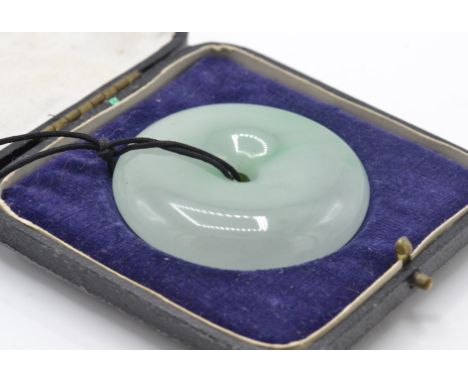 A large Chinese Jade Bi roundel pendant. The Bi pendant formed of a pierced roundel of Jade strung upon a string cord within 