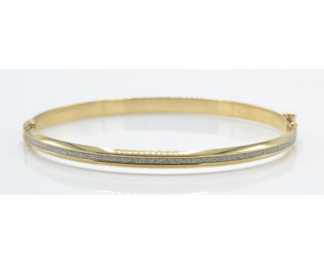 A hallmarked 9ct white and yellow gold and bracelet / bangle. The bracelet having white gold textured diamond cut channel wit