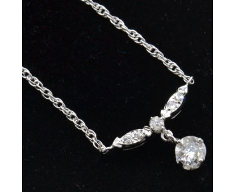 A 14ct white gold and diamond pendant necklace. The necklace strung with a brilliant cut diamond drop surmounted by diamond s