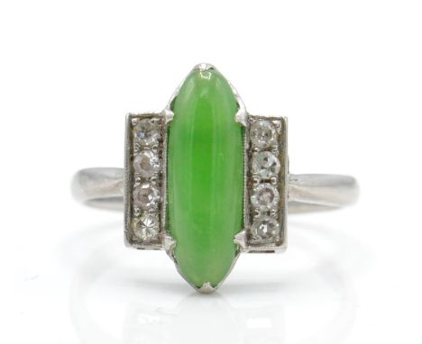 An Art Deco platinum, diamond and nephrite ring. The ring set with a green cabochon possible nephrite. Flanked by two rows of