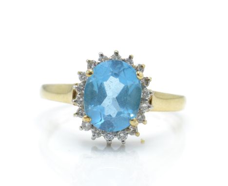 A hallmarked 9ct gold topaz and diamond cluster ring. The ring set with a central large oval mixed cut topaz surrounded by a 