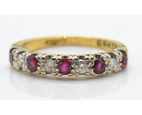 An 18ct gold ruby and diamond band ring. The ring set with alternating ruby and diamonds in a scalloped pronged setting with 