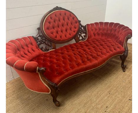 A Victorian carved and button backed salon sofa on scrolling feet and castors. (195cm L x 94cm H x 86cm D)