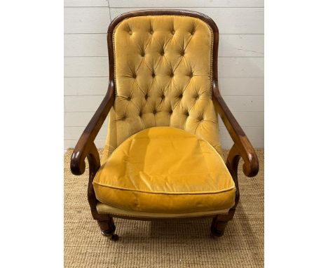A button back library chair on castors upholstered in a mustard yellow