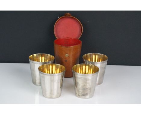 A set of four silver plated stirrup cups in brown leather case. 