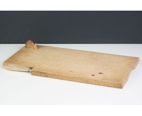 A wooden cheese board and cheese knife in the style of Mouseman Robert Thompson. 