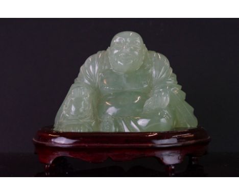 A carved jade figure in the form of a Buddha on fitted stand. 