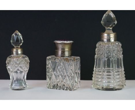 A collection of three cut glass and silver topped scent bottles to include an enamel example. 