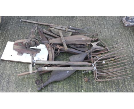 An assortment of vintage farm tools. To include horse lines, hay forks, an axe, etc