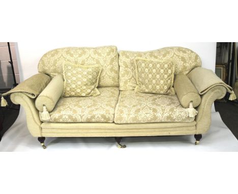 A large cream sofa. With curved back, scrolling arms, raised on turned supports to casters. L200cm x D100m x H85cm