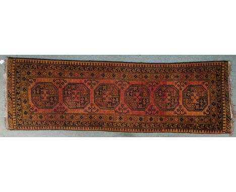 A terracotta ground Bokhara style runner with six octagonal style medallions with multiple borders, 238cm long x 75cm wide&nb