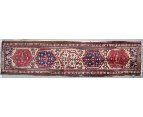 A cream ground Caucasian style runner with multicoloured diamond shaped medallions withing multicolour floral geometric borde