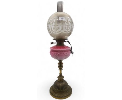 A brass and glass oil lamp with buttons marked for Young's screw fittings, with a pink milk glass reservoir Condition Report: