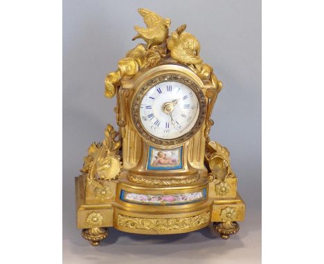 French ormolu figural mantel clock mounted by a fallen torch and turtle doves, flanked by musical instruments and a Roman sol