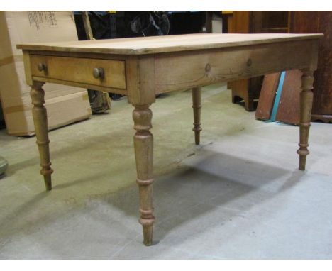A Victorian stripped pine kitchen table of rectangular form fitted with a frieze drawer, raised on ring turned and tapered su