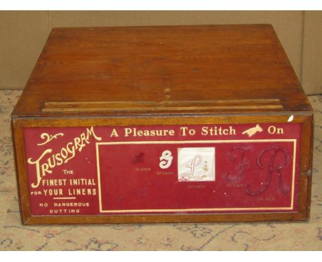 A vintage oak shop counter-top haberdashery cabinet enclosing a full length drawer, the front elevation with original panel a