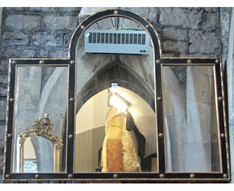 An antique style wall mirror of rectangular and arched form, the ebonised frame with repeating gilt mouldings enclosing three