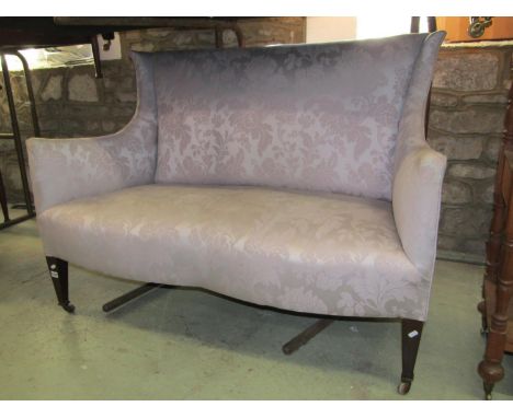 An Edwardian two seat sofa with shaped outline, shallow winged back, serpentine shaped seat and light blue repeating floral p