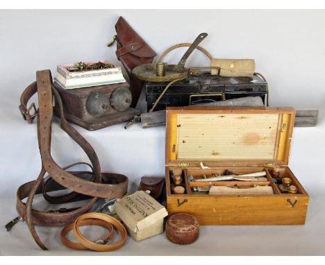 A box containing leather straps and belts, sewing items, a tin money, a paint box, compass and a leather first World War gun 