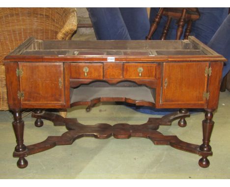 An antique walnut stand fitted with an arrangement of drawers and cupboards, under shelf, turned supports united by a shaped 