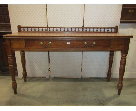 An Edwardian oak hall/serving table with raised turned baluster rail over a frieze drawer raised on ring turned and tapered s